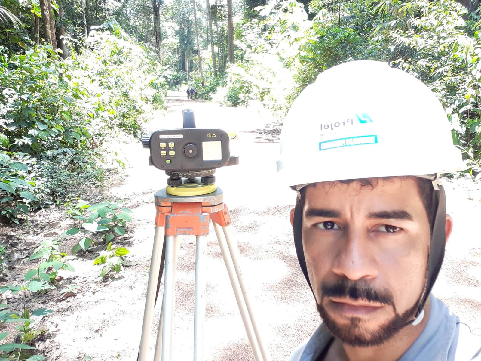 Topógrafo com equipamento em levantamento dentro de área de mata