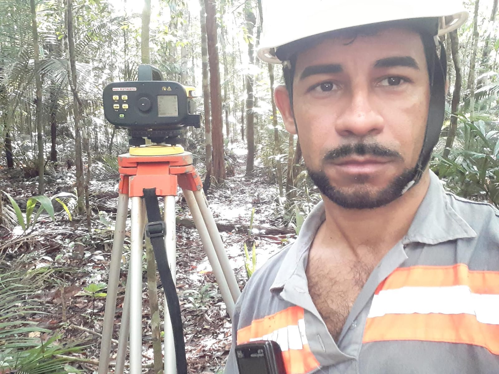 Engenheiro topógrafo com equipamento em floresta
